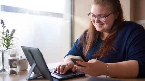 Bigger girl smiling while checking her cellphone at a cafe Stock Photos