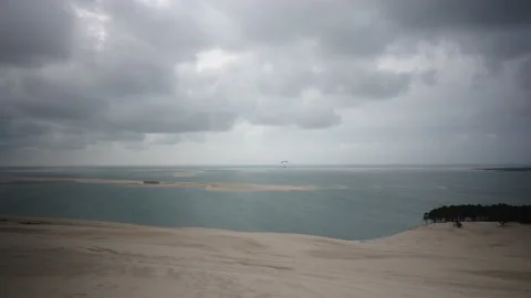 Biggest sand dune du pilat in France, one person paragliding, bad weather Video stock 233597352