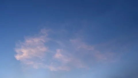 A bight blue summer sky with a few clouds lit by the late day sun drifting Stock Footage 311128562