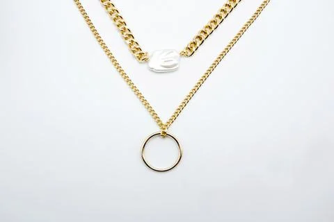 Bijouterie. Two gold chains and a beautiful shiny white gem on a white Fotos Stock