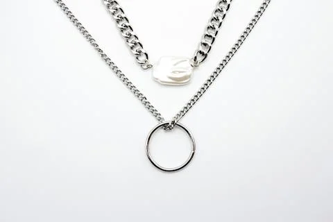 Bijouterie. Two silver chains and a beautiful shiny white gem on a white Fotos Stock