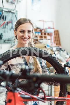 Bike Mechanic Woman Looking Through The Wheel Of Bicycle