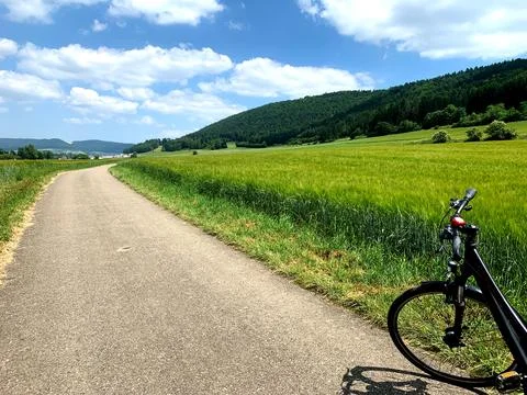 A bike rests against the path while bright green fields stretch under a cle.. Stock Photos