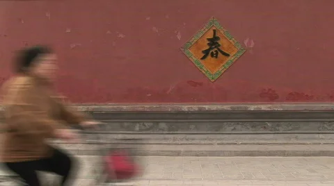 Bike Riding past a Red Wall with Chinese Text at the White Cloud Temple in China Stock Footage