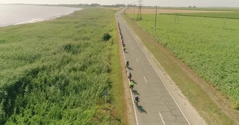 Bike trip on the road between the fields, top view. A bicycle column rides by Video stock 78937361