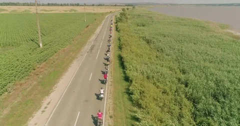 Bike trip on the road between the fields, top view. A bicycle column rides by Stock Footage 78937534