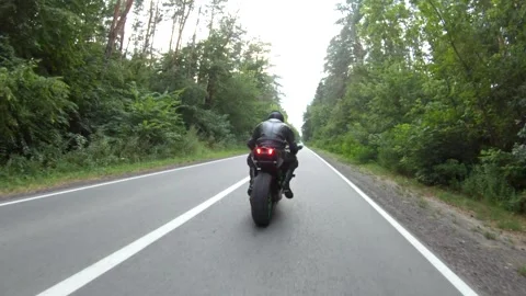 Biker is accelerating at motorcycle on empty country road. Man ride on motorbike Stock Footage 306929065