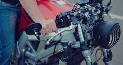 Biker activates the ignition of the motorcycle on the side of the highway. Close Stock Footage 92270381