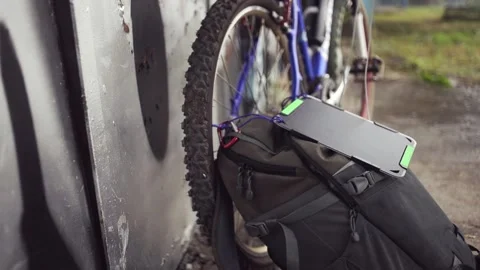 Biker charges smartphone using solar panel attached to his backpack. Video stock 157348832