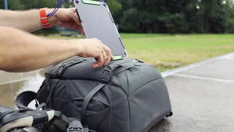 Biker charges tablet using solar panel on his backpack. Stock Footage 157333309