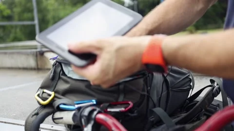 Biker charges tablet using solar panel on his backpack. Stock Footage 157333343