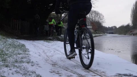 Biker cycles on canal towpath after winter snowfall Stock Footage 148673553