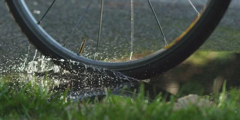 Biker cycling through a puddle and splashing water Stock Footage 103747976
