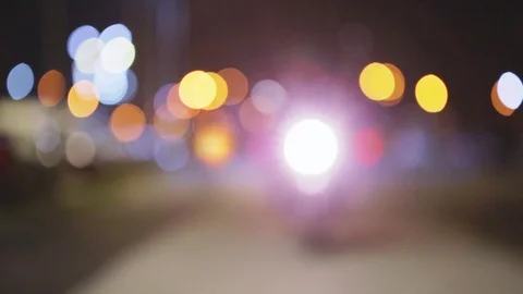 Biker going to stop. White lamp of motorcycle. Blurred bokeh out of focus night Stock Footage 76878585