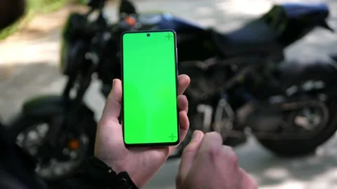 Biker hands using mobile phone with blank green screen chroma key with gestures Stock Footage 156566265