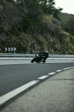 Biker leaning into a sharp turn on a forest road Stock Photos