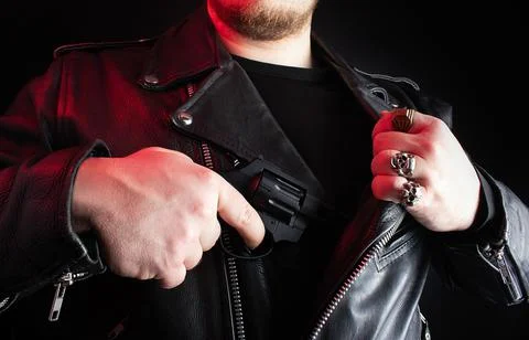 Biker in leather jacket pulling out revolver. Stock Photos