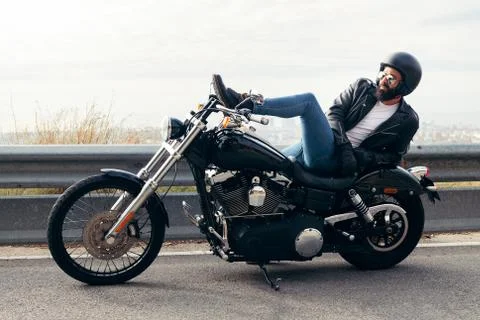 Biker lying down on a motorcycle far from the city Stock Photos