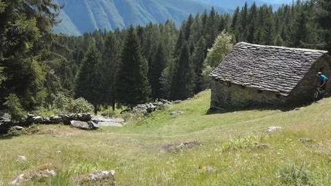 Biker on a mountain path and chalet Stock-Footage 114174796