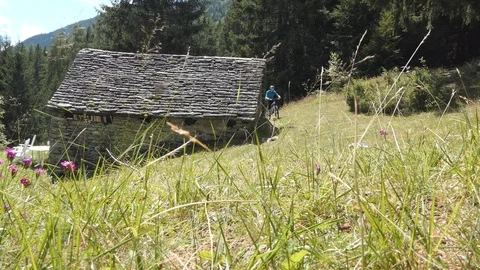 Biker on a mountain path and chalet Video stock 114174908