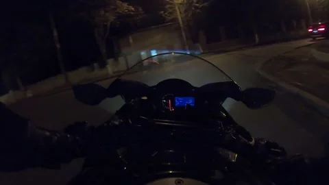 Biker navigating through a vibrant night cityscape on a motorcycle, showcasing Stock-Footage 329680440