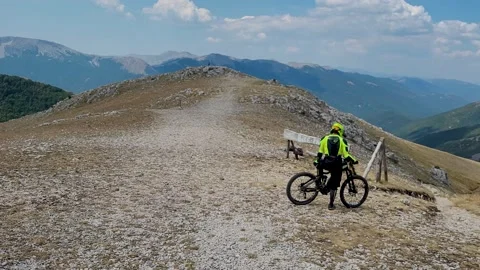 Biker on a peak of mountain is ready to start a downhill Stock Footage 159023727