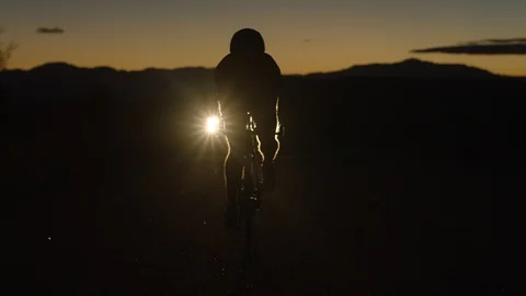 Biker pedaling towards the camera as it moves backwards at night Stock Footage 106467208