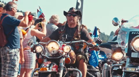 Biker with plaits making the hand horns sign while driving on his motorcycle Stock Footage 68628653