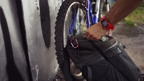 Biker pulling out solar panels from backpack and attaching it to carabiner. Video stock 157333155