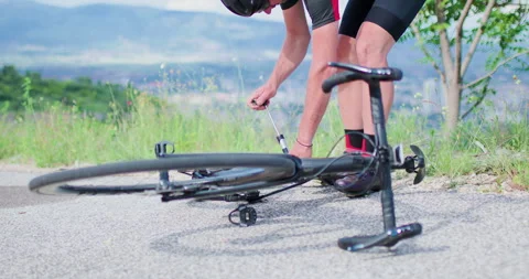 Biker repairs flat tire on road bike during journey in nature stops on asphalt Stock Footage 339493856