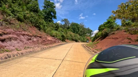 A biker is riding a motorcycle fast on a small concrete road in the forest Stock Footage 249641339