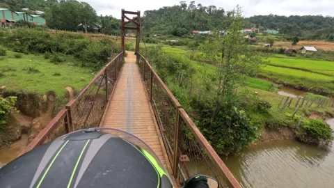 A biker is riding a motorcycle on a small shaking dangerous suspension bridge Stock-Footage 249999193