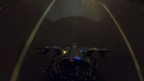 Biker riding powerful motorcycle through dimly lit city streets at night Video stock 324752947