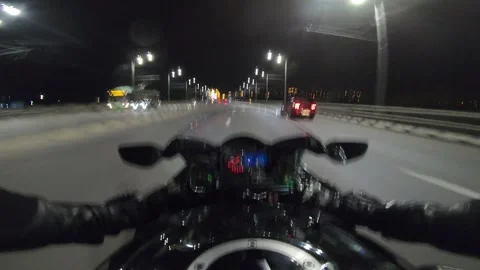 Biker riding a powerful motorcycle through a vibrant city at night Stock Footage 324753057