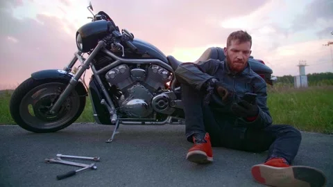 Biker on the side of the road with a broken chopper calls to support Stock Footage 154817845