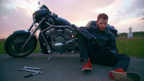 Biker on the side of the road with a broken chopper calls to support 스톡 동영상 154916126