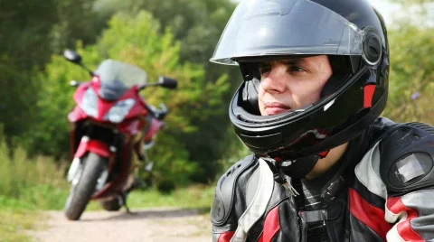 Biker sits near motorcycle, see and close visor on it helmet Stock Footage