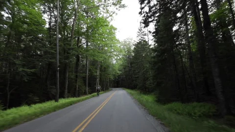 A biker speeds by on the side of the road. Stock Footage 148126622