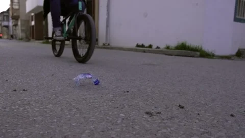 A biker taking a plastic bottle from the street while riding a street bike Stock Footage 139465408