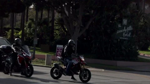Biker talking on the phone at a traffic light outside Beverly Hills Hotel in Los Stock Footage 135797848