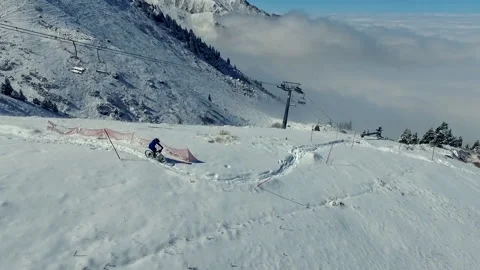 Biker in winter cloudy mountains biking riding bicycle in the snow. Aerial view Vidéo 169535618