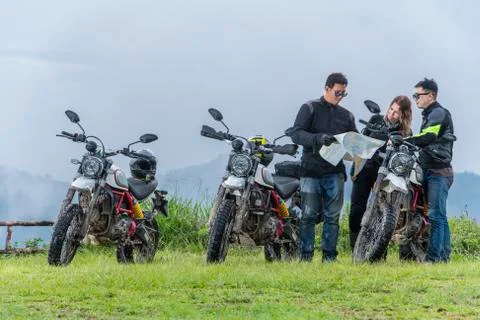 Bikers checking map next to off road motorcycles, mountains in background, Stock Photos