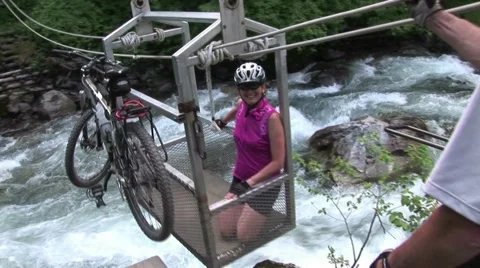  Bikers Crossing River with Cable Car in Rocky Mountains Video stock 53146761