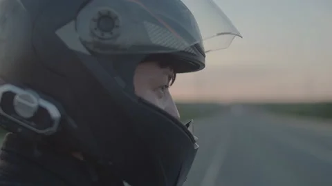 Biker's face is a closeup, side view. Male motorcyclist closes his helmet over Stock Footage 157309367