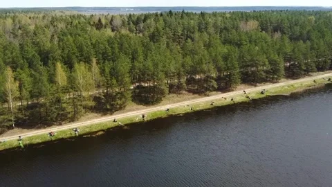 Bikers ride along a river path surrounded by trees in a forested area Stock Footage 328992815