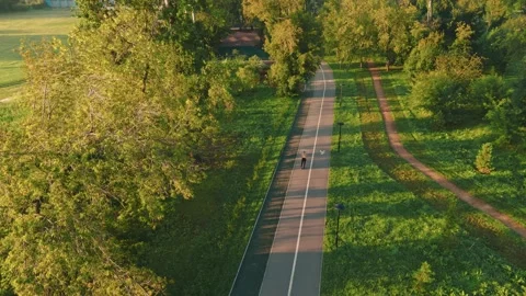 Biking along a scenic pathway surrounded by trees and greenery in summer 스톡 동영상 285155018