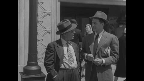 Bikini Atoll 1940s: Two men in suits and fedoras stand talking on a city Stock Footage 344295778