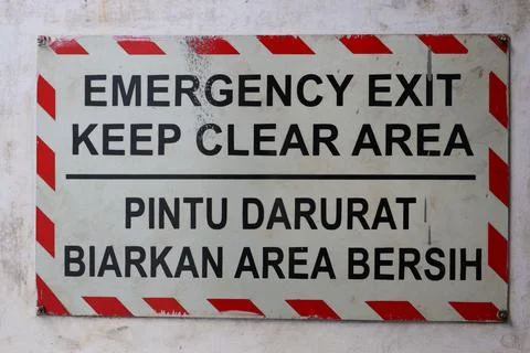 Bilingual Emergency Exit Keep Clear Warning Sign on Wall. Stock Photos