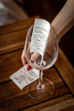Bill for payment in the glass. The girl's hand holds a receipt for payment in Stock Photos
