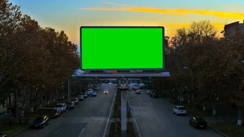 A billboard with green chroma key on the background of fast moving cars Stock Footage 87615510